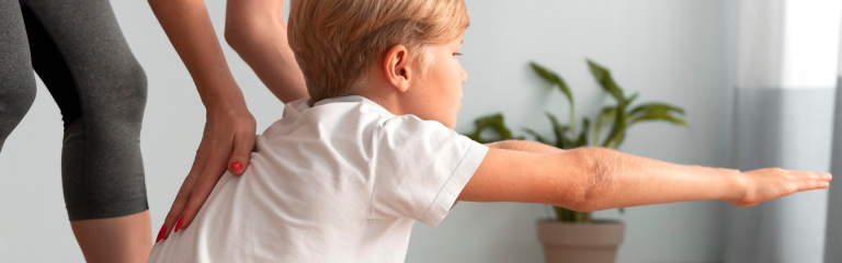 Foto di un bambino che viene guidato dal fisioterapista nell'effettuare un esercizio di ginnastica posturale