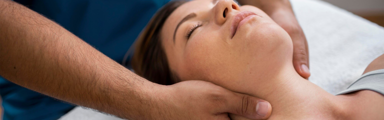 Foto di trattamento fisioterapico per osteoporosi effettuato dal fisiatra. Nell'immagine, le mani del medico massaggiano il collo di una donna distesa.